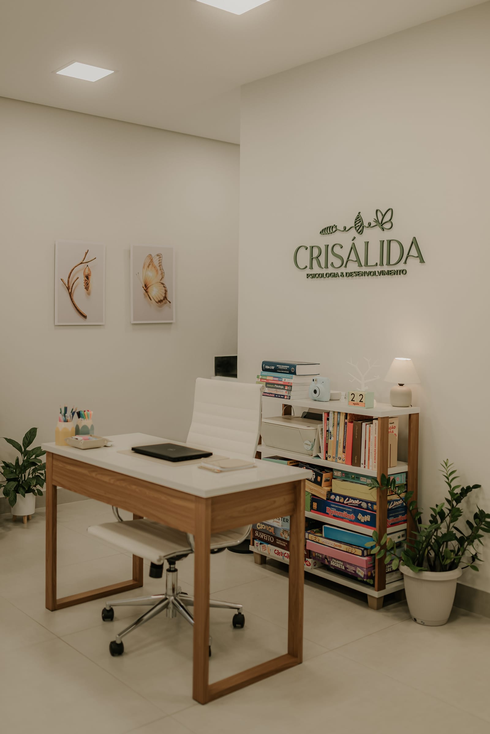 Vista geral do consultório, com escrivaninha, estante de livros e iluminação suave
