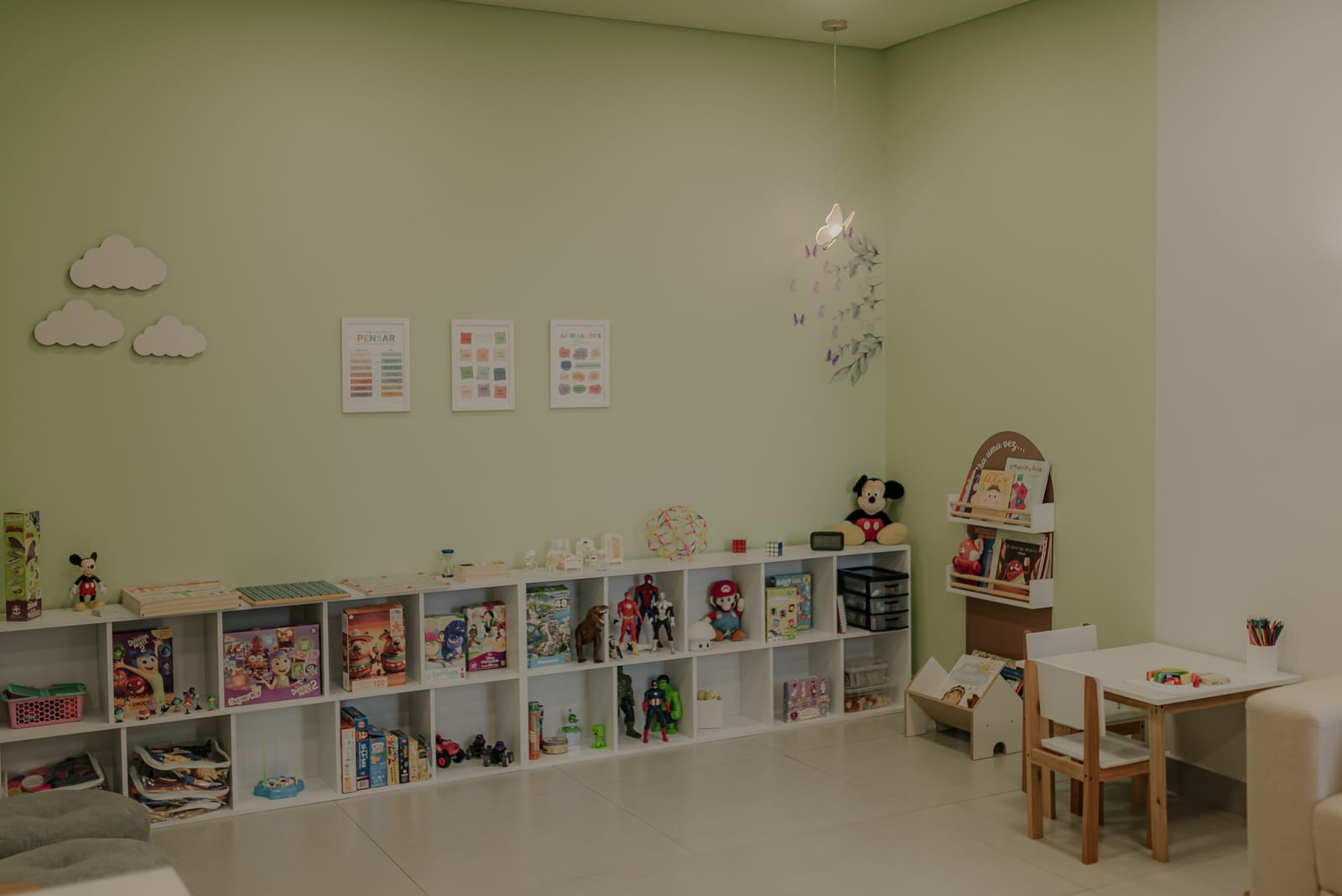 Sala de atendimento infantil da Crisálida, com parede verde e brinquedos organizados