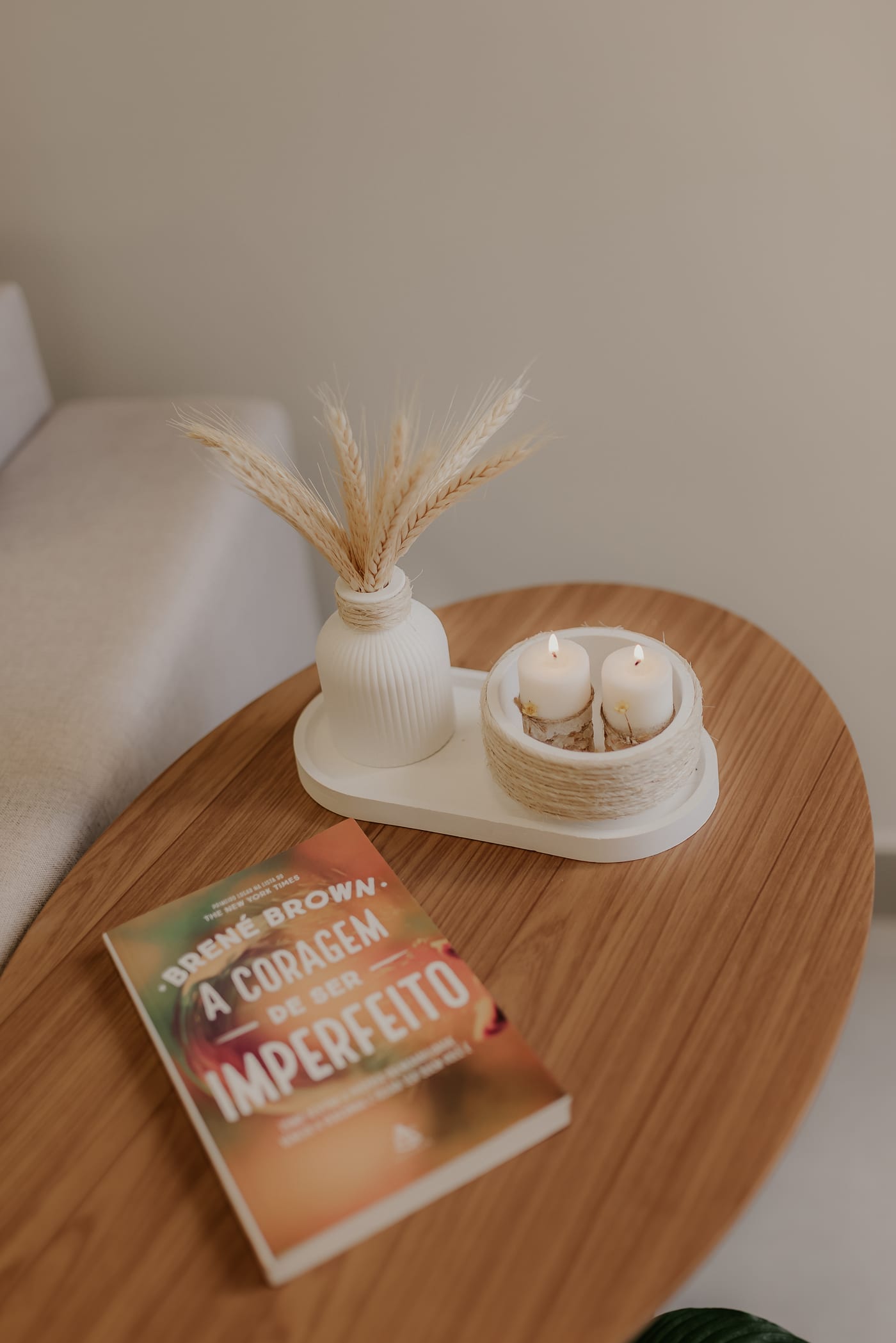 Mesa de apoio com vela, difusor e livro ao lado da poltrona de atendimento